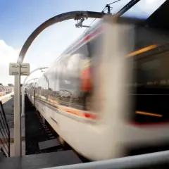 Treno in corsa sulla borghesiana metro c, con riflessi nel cielo e luci interne.