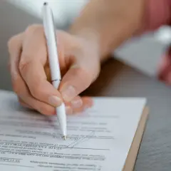 Dłoń podpisuje aneks do umowy najmu okazjonalnego. Dokument zawiera pola dotyczące danych podatkowych i działalności gospodarczej.