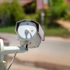Kamera do monitoringu domu, zamontowana na zardzewiałym słupku, czuwa nad otoczeniem.