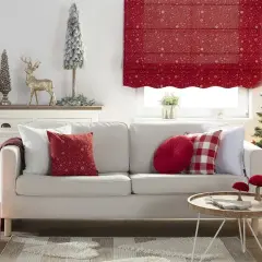 Przytulny, świąteczny salon z białą kanapą, choinką i ozdobami. Dominują akcenty w kolorze czerwonym, tworząc ciepłą atmosferę.