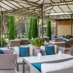 Terrasse de restaurant chic avec mobilier d'extérieur confortable et jardin verdoyant en arrière-plan.