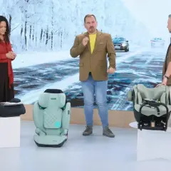 Trzech prowadzących prezentuje foteliki samochodowe, w tym fotelik antymandat. Tło przedstawia zimową drogę.