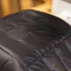 Ein kleines Loch in der schwarzen Daunenjacke wurde mit einem Flicken repariert.