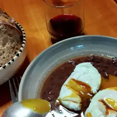 Œufs meurette, un plat d'origine française, servis avec du pain et du vin rouge.