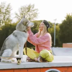 Dziewczyna z alaskan malamute na deskorolce w skateparku. Idealne miejsce, gdzie na spacer z psem Warszawa.