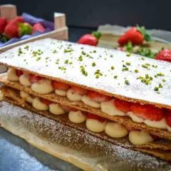 Ein köstliches Mille-feuille mit frischen Erdbeeren und Sahne, bestreut mit Puderzucker und Pistazien.