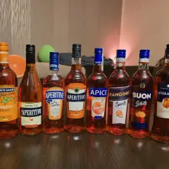 Rząd butelek z pomarańczowym aperitivo, w tym Monte Santi i Aparancio. Zastanawiasz się aperol co to? To popularny włoski aperitif!