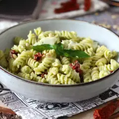Un plat de pâtes fusilli au pesto, tomates séchées et pignons de pin. Une idée parfaite pour savoir que faire avec un reste de pâtes !