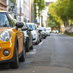 Żółty samochód zaparkowany na ulicy w rzędzie innych aut.