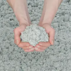 Dłonie trzymają grudkę celulozy, materiału do ocieplenia domu.