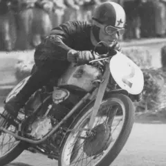 El piloto de carreras Carlo Ubbiali inclinado en su moto con el número 2, compitiendo con determinación.