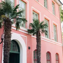 Hoby Kulle Herrgård i rosa nyanser med gröna fönster och palmer som ger en oväntad känsla.