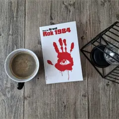 Kawa i książka "Rok 1984" George'a Orwella. Biografia autora w tle.