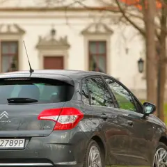 Szary Citroen C4 1.6 HDi zaparkowany przed zabytkowym budynkiem.