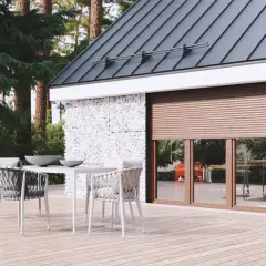 Brązowe rolety skutecznie chronią przed słońcem, tworząc przytulną atmosferę na tarasie z drewnianą podłogą i kamiennymi ścianami.