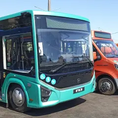 Nowe autobusy i samochody dostawcze stoją obok siebie. Jeden z autobusów, w kolorze turkusowym, ma otwarte drzwi, gotowy do podróży z Augustowa do Łodzi.