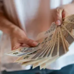 Dłonie trzymają wachlarz banknotów 200 zł. To symbol nagrody jubileuszowej za 40 lat pracy w budżetówce, zasłużone docenienie wieloletniego trudu.