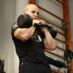 Mężczyzna ćwiczy z kettlebell, pokazując, jakie partie mięśni ćwiczyć razem dla efektywnego treningu.