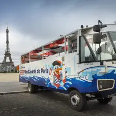 Un bus amphibie "Les Canards de Paris" prêt pour un tour hop on hop off, avec la Tour Eiffel en arrière-plan.
