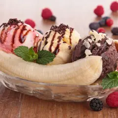 Ein klassisches Banana Split Eis mit drei Kugeln Eis, Banane, Beeren und Schokoladensauce.