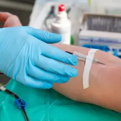 Ręka w błękitnej rękawiczce medycznej pobiera krew. To ważny moment, bo każda kropla, niezależnie od grupy krwi, ratuje życie.