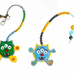 Zwei lustige Monster-Anhänger mit Perlenketten zum **rechenkette basteln**. Ein grünes und ein blaues Monster mit mathematischen Symbolen an den Füßen.