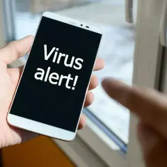 Dłoń trzyma smartfon z napisem "Virus alert!". Czas zainstalować antywirus na telefon.
