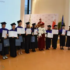 Absolwenci w togach i biretach odbierają dyplomy. Uroczystość wręczenia tytułów licencjat.