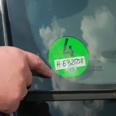 Palec wskazuje na zieloną winietę z numerem 4 i rejestracją H-EP2508, naklejoną na przedniej szybie samochodu w Niemczech.