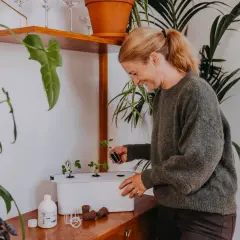 Glad kvinna planterar små plantor i ett hydroponiskt system. Hon använder en liten kruka med jord för att plantera en ny planta, kanske för att utöka sin harvy 6-odling.