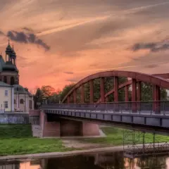 Zachód słońca nad Wartą w Poznaniu, z katedrą i mostem Jordana w tle.