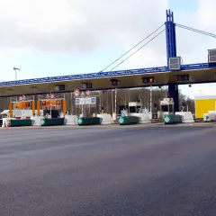 Péage d'autoroute avec plusieurs voies de passage. Une voiture attend à une borne de péage.