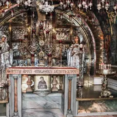 Wnętrze kaplicy Grobu Pańskiego, miejsca, gdzie umarł Jezus. Złote zdobienia, ikony i świece tworzą atmosferę świętości.