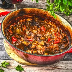 Herzhaftes Schweinegulasch im roten Bräter, bereit zum Servieren. Ein köstliches Schweinegulasch Rezept für gemütliche Abende.