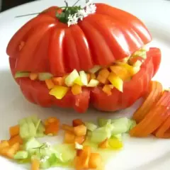 Un tomate cœur de bœuf farci de légumes croquants, servi avec des quartiers de tomate et une vinaigrette légère. Un délice estival !