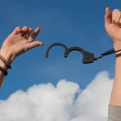 Ręce wzniesione ku niebu, uwolnione z kajdanek. Symbol wolności i powrotu do trybu ambulatoryjnego po trudnym okresie.
