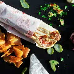 Pyszny kebab w tortilli z chrupiącymi chipsami i świeżymi dodatkami, gotowy do zjedzenia.