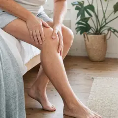 Donna si tocca il ginocchio, forse per un problema al liquido sinoviale.
