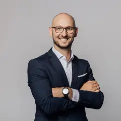 Uśmiechnięty mężczyzna w okularach i garniturze, z rękami skrzyżowanymi na piersi. Idealne pozy do zdjęć męskie.