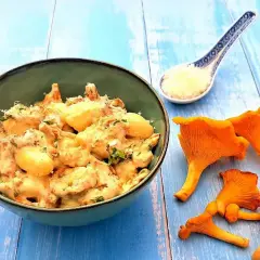 Wegańskie gnocchi z kurkami w kremowym sosie, posypane parmezanem, na niebieskim tle.