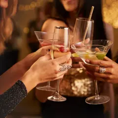 Brindis de mujeres con copas de cóctel en una celebración. La barra libre de la boda promete diversión y glamour.