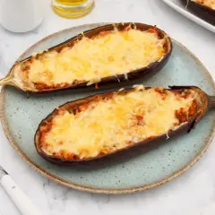 Dos mitades de berenjenas rellenas de atún, gratinadas con queso derretido, servidas en un plato azul.