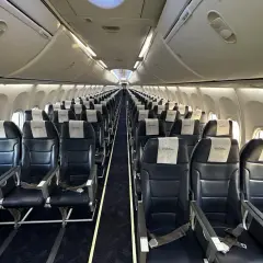 Puste wnętrze samolotu Enter Air. Rzędy ciemnych foteli z zagłówkami z logo "enter." czekają na pasażerów.