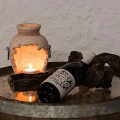 Kerzenlicht erhellt eine Flasche Wein, die auf einem Holzstück liegt. Hoffentlich wurde kein schlechten wein getrunken.