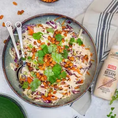 En fräsch asiatisk sallad med krispig vitkål, rödkål och morötter, toppad med rostade nötter och koriander. Serveras med Felix mörkrostade sesamdressing.