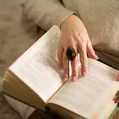 Kobieta z pierścionkiem na palcu czyta książkę, szukając pocieszenia i siły w modlitwie za chorych.