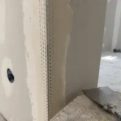 Angoli in cartongesso pronti per la stuccatura. Un angolo è rinforzato con nastro metallico, mentre l'altro è già parzialmente stuccato.
