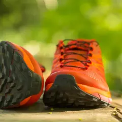 Leuchtend orange Wanderschuhe mit grobstolliger Sohle, bereit, neu besohlt zu werden für neue Abenteuer.