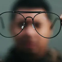 Osoba trzyma przed twarzą okulary. Nowe okulary dziwne widzenie, jakby świat przez nie wyglądał inaczej.