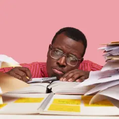 Un homme fatigué, entouré de piles de documents, semble avoir un avis de départ. Il repose sa tête sur un livre ouvert, l'air dépassé par la paperasse.